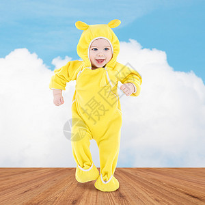 人,孩子,成就幸福的穿着黄色西装的快乐宝宝木地板蓝天背景上迈出步图片
