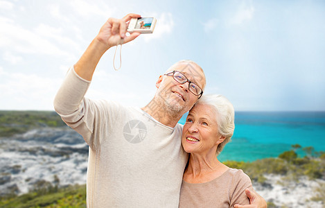 龄,旅游,技术人的老夫妇带着相机海滩背景的街道上自拍图片