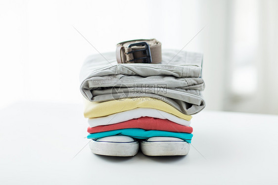 衣服,个人工作人员物品的折叠衬衫,裤子,皮带鞋子家里的桌子上图片