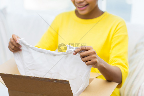 人,送货,商业,航运邮政服务的快乐的非裔美国轻妇女纸板箱包裹家里衣服图片