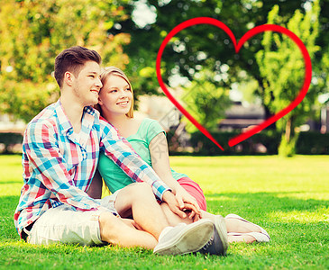 假日,情人节,约会爱情的快乐的夫妇坐草地上的夏季公园,红色的心形图片