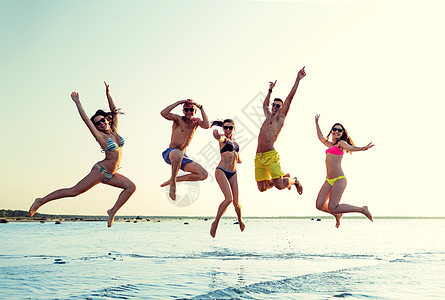 友谊,海洋,暑假,假期人们的群微笑的朋友穿着泳装太阳镜海滩上跳跃图片