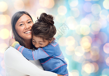 人,母亲,家庭收养的快乐的母亲女儿拥抱蓝色假日灯光背景图片