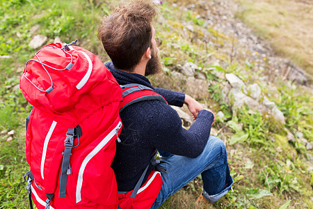 冒险,旅行,旅游,徒步旅行人的男人徒步旅行者与红色背包坐地上图片