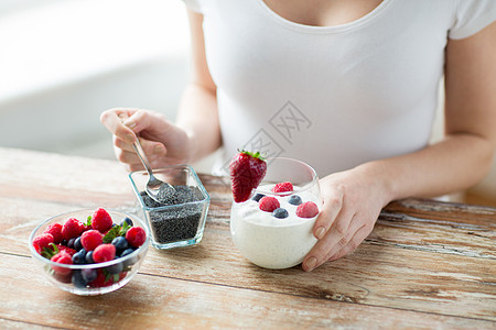 健康饮食,素食,饮食人的密切妇女的手与酸奶,浆果辣椒种子勺子图片