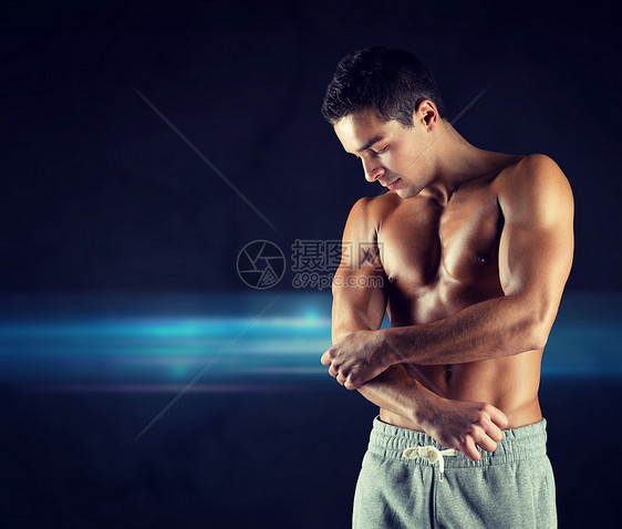 疼痛,运动,健美,健康人的轻的男健美运动员触摸受伤的肘部黑暗的背景图片