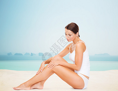 人,美,水疗度假美丽的女人穿着棉质内衣,触摸她的腿无限的边缘游泳池背景图片