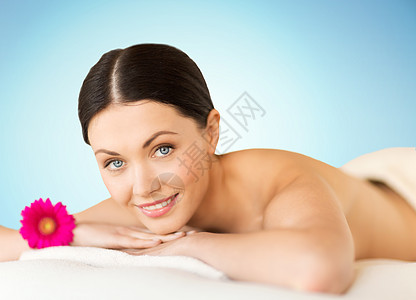 人,美容,水疗身体护理快乐的美丽女人躺按摩台上的水疗蓝色背景图片