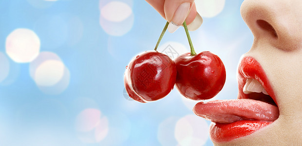 人,夏天,女人的嘴与嘴唇舌头吃成熟的红樱桃蓝光背景图片