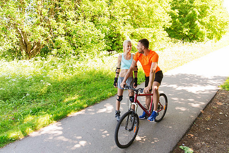 健身,运动,夏天,人们健康的生活方式的快乐的夫妇与滚轮自行车骑户外交谈夏天图片
