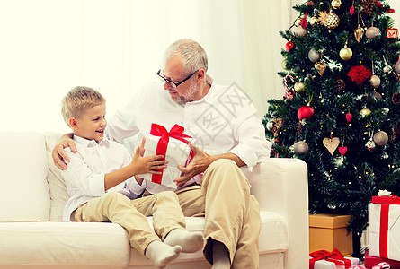 家庭,假期,代,诞节人的微笑的祖父孙子坐家里的沙发上的礼品盒图片