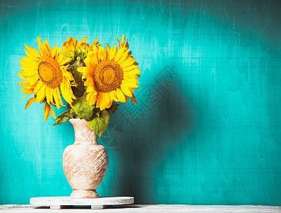 向日葵蓝色木制背景的花瓶图片