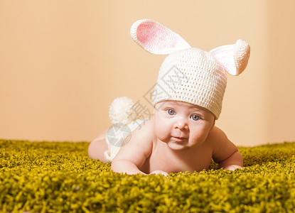 三个月的婴儿躺他的肚子上,就像草地地毯上的复活节兔子复活节小兔子图片