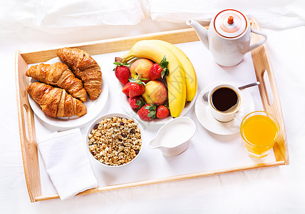 床上吃早餐托盘上咖啡牛角包谷类食品水果图片