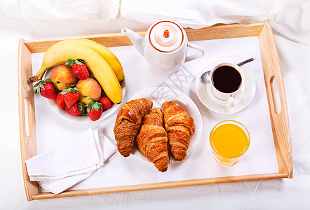 床上吃早餐托盘上咖啡牛角包水果图片