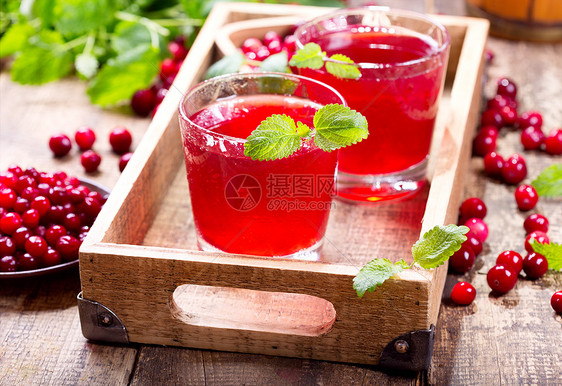 杯蔓越莓汁新鲜薄荷放木桌上图片