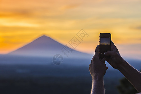 以手机火山为背景的人日出时,巴厘岛,印度尼西亚图片