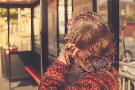 个轻的女人个阳光明媚的日子公共汽车站等着图片