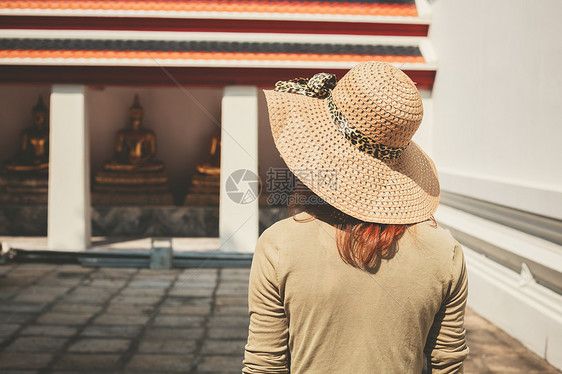 个戴帽子的轻女人正探索座佛教寺庙图片