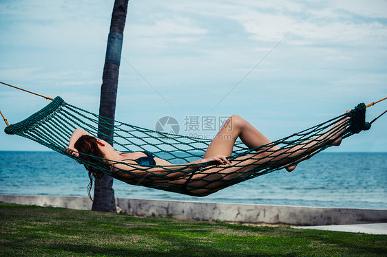 一个年轻的女人正海边的吊床上放松图片