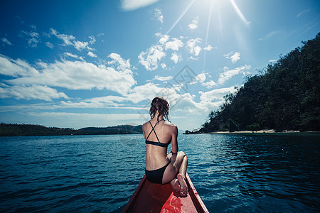 个穿着比基尼的感轻女人坐热带岛屿附近的艘小船上图片