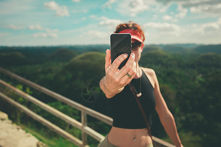 个轻的女人正个热带的山上用智能手机自拍图片