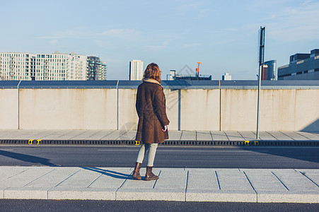 一个年轻的女人站路上,冬天盯着个城市的天际线图片