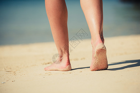 个轻女人海滩上散步时的脚图片