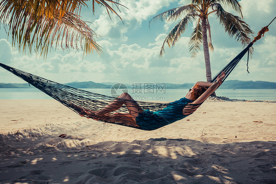 个轻的女人正热带海滩上的吊床上放松图片