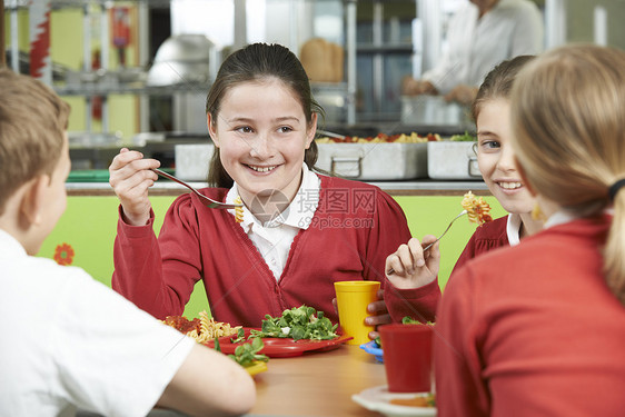 群学生坐学校自助餐厅的桌子上吃午饭图片