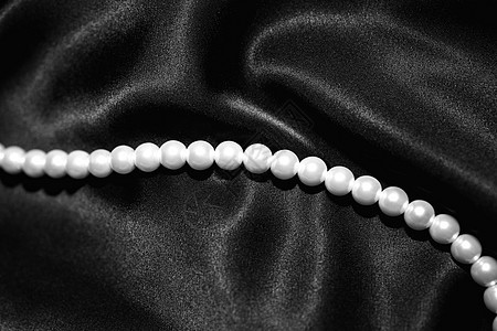 白色珍珠项链上的黑色缎子特写图片