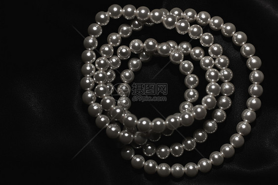 白色珍珠项链上的黑色丝绸特写图片