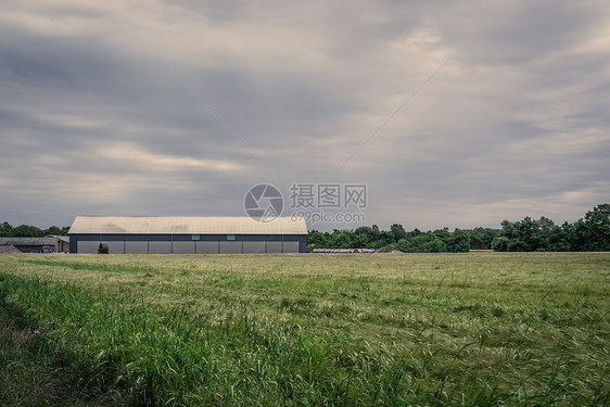 多云天气下,农场田野上谷仓图片