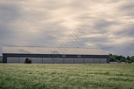 多云天气下绿色田野上的农业谷仓图片