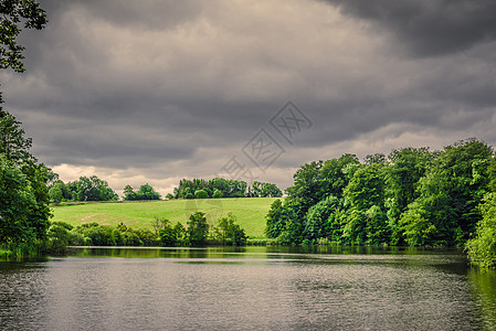 湖泊风景与绿色的田野黑暗的多云天气图片