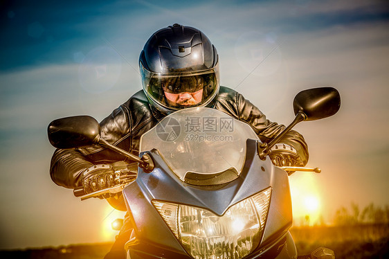 骑自行车的头盔皮夹克赛车道路上与太阳背景图片