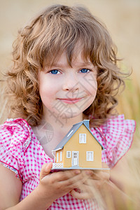 秋天的黄色背景下,孩子手里着房子房地产图片