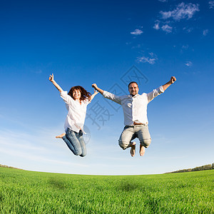快乐的夫妇绿色的田野上着蓝天跳暑假图片