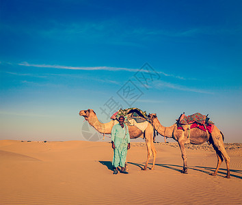 复古时尚风格的旅行形象拉贾斯坦邦旅行背景印度来勒骆驼司机与骆驼沙丘的塔尔沙漠贾萨尔默,拉贾斯坦邦,印度图片