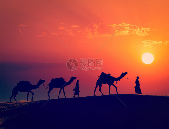 复古效果过滤了拉贾斯坦旅行的时尚风格形象两个印度来客骆驼司机与骆驼轮廓沙丘的塔尔沙漠日落贾萨尔默,拉贾斯坦邦,印度图片