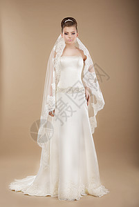 轻的新娘穿着棕色背景的婚纱图片