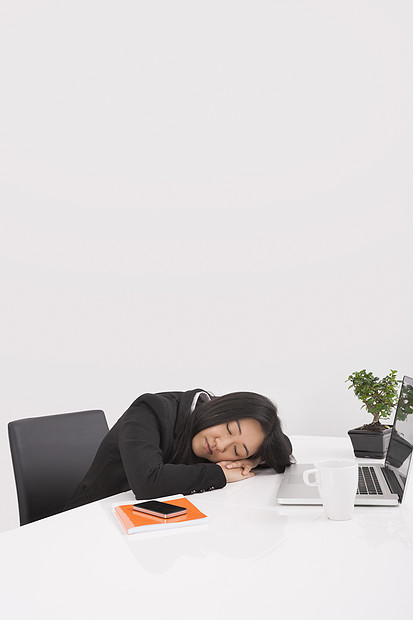 疲惫的女商人办公室的办公桌前休息