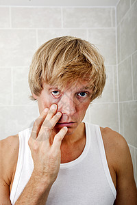 浴室里困倦的男人拉眼皮的肖像图片