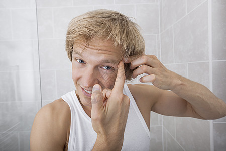 浴室里男人额头上挤压疙瘩的肖像背景图片