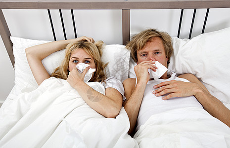 患感冒躺床上的夫妇的肖像图片