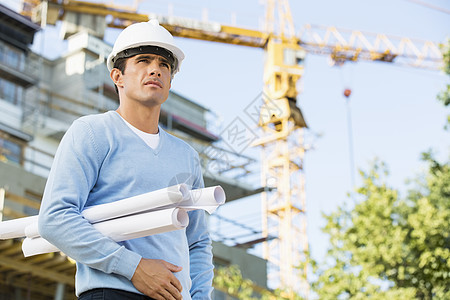 男建筑师建筑工地站着时,着蓝图图片