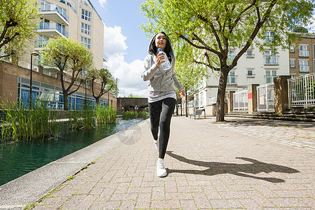 全长适合的轻妇女慢跑运河建筑物图片