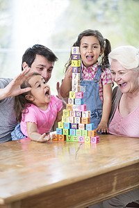 幸福的多代家庭与安排的积木餐桌上的房子图片