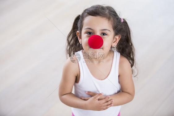 可爱的小女孩家里戴着小丑鼻子的肖像图片