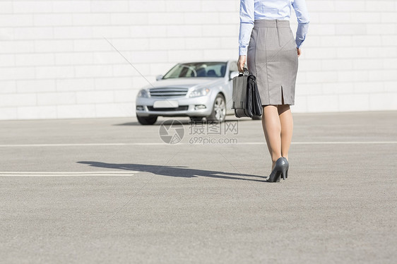 低段的女商人带着公文包,街上走向汽车图片